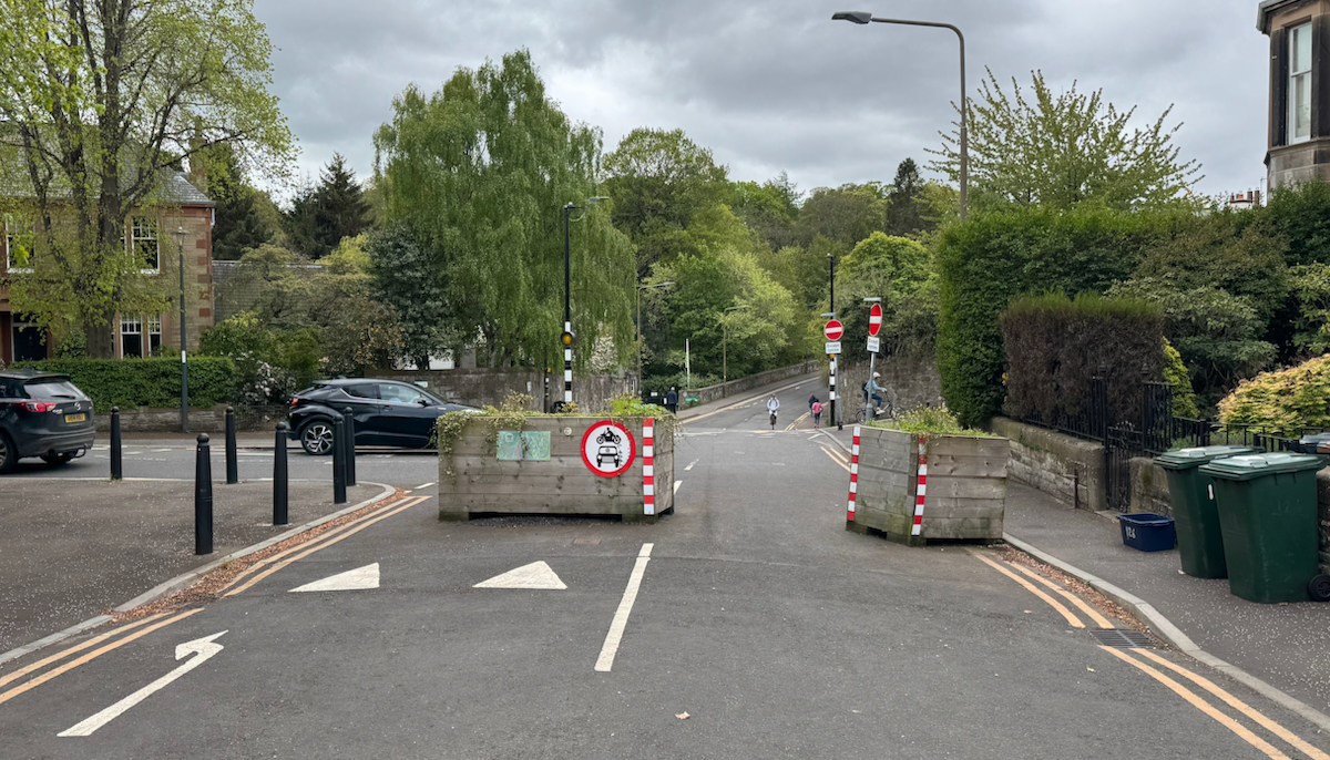 A pair of wooden planters block access to a road but leave space for cycles to pass through